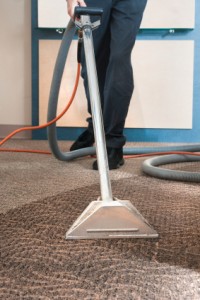 closeup of technician using vacuum on carpet cleaner
