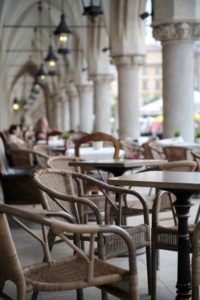 outside patio of large beautiful building with patio seating large columns and pendant lighting